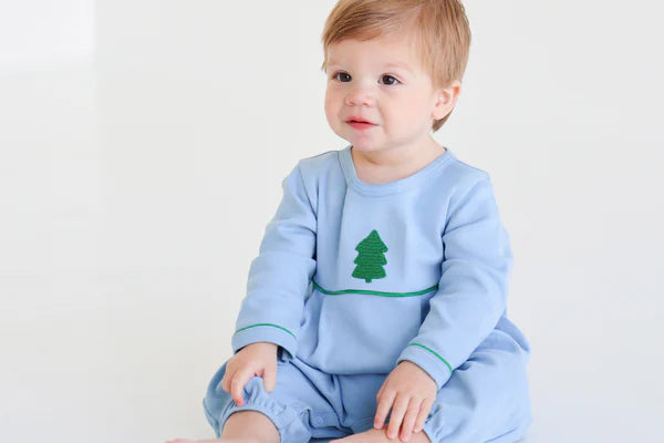 Baby in a blue outfit with a tree design on a white background