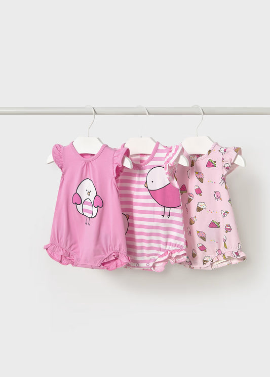 Three pink children's dresses on hangers against a white background