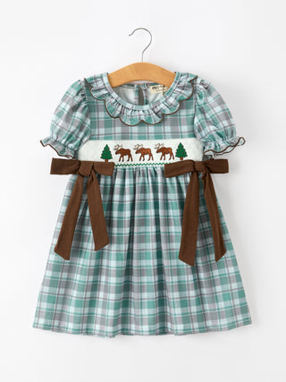 Plaid dress with moose and tree design on a hanger against a white background
