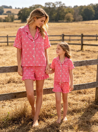 Woman and child in matching pink pajama sets standing in a field.
