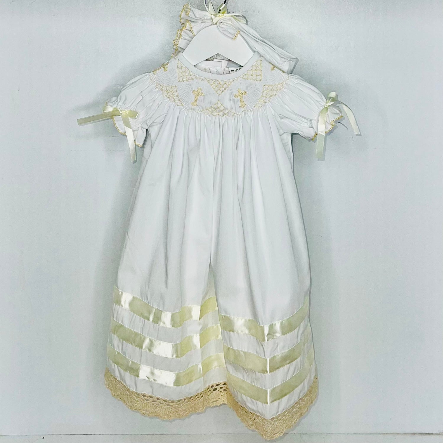 White baby dress with gold embroidery and trim on a white background
