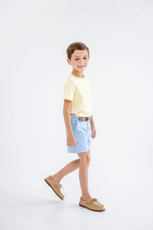 Young boy wearing a yellow shirt and light blue shorts on a white background