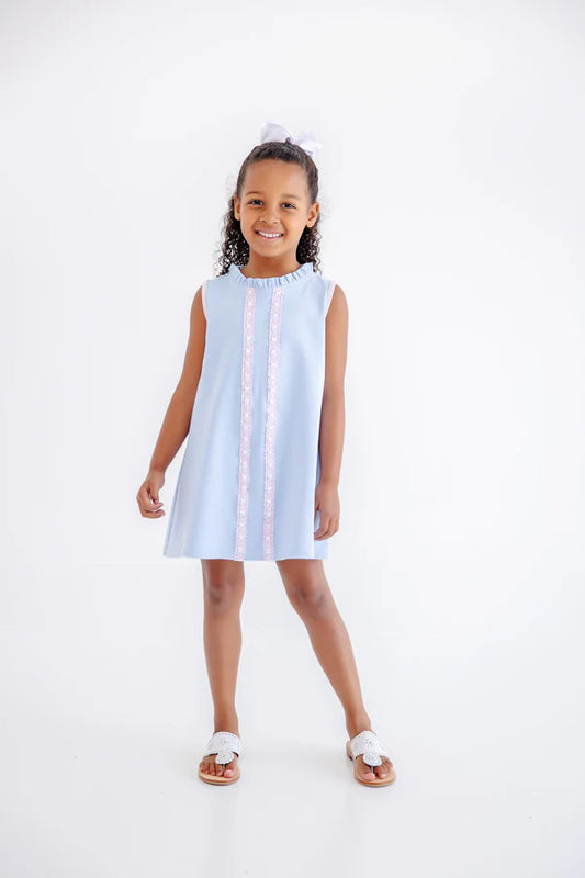 Young girl wearing a light blue dress with white trim on a white background