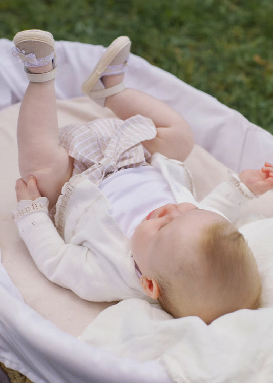 Baby lying on a white blanket with a blurred green background