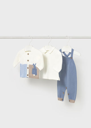 Children's clothing set with blue overalls and white shirt on hangers against a white background