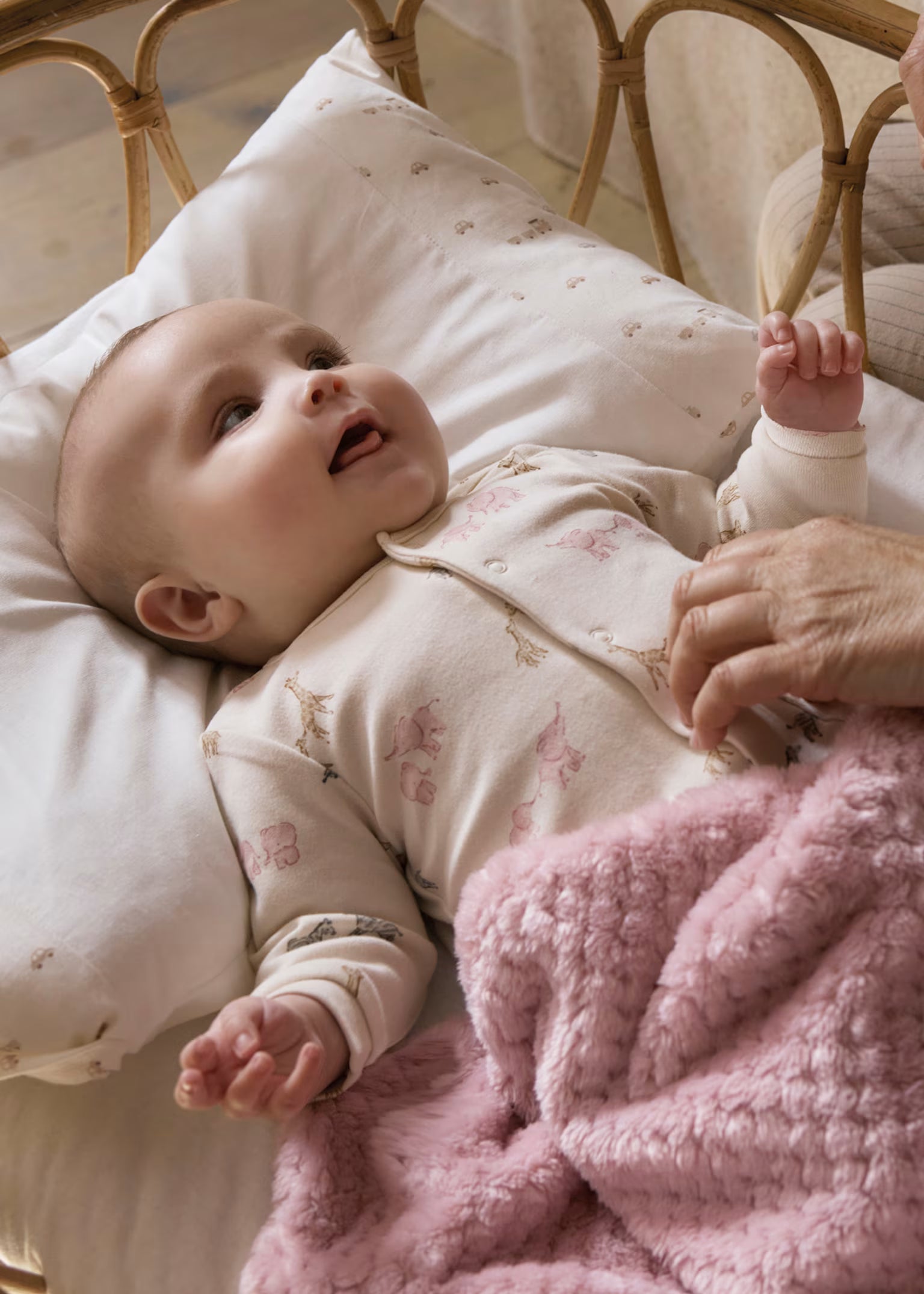 Baby lying on a bed with pink blanket and white pillow