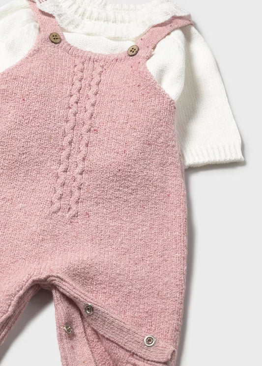 Pink knitted baby romper with white top on a light background